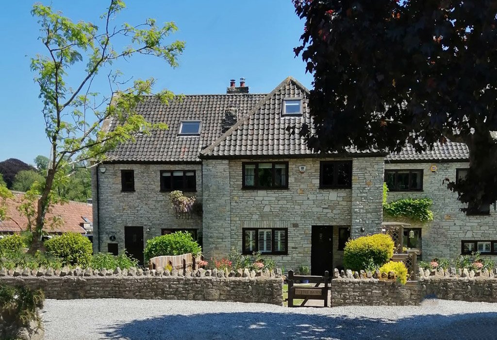 Charming stone house with garden and blue sky.