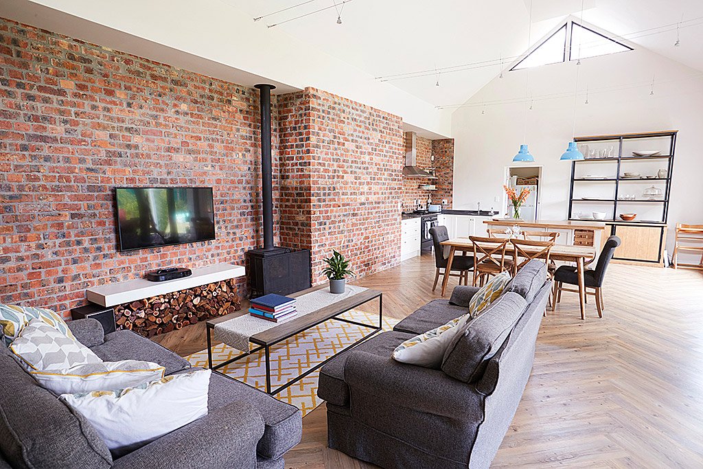 Spacious open-plan living room with brick walls in barn.