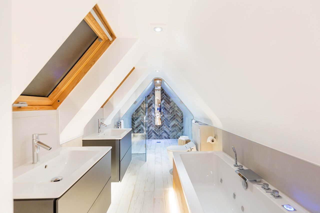 Modern attic bathroom with skylight and bathtub.