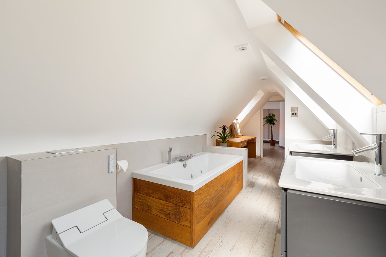 Modern bathroom with wooden bathtub and skylight, in new loft project