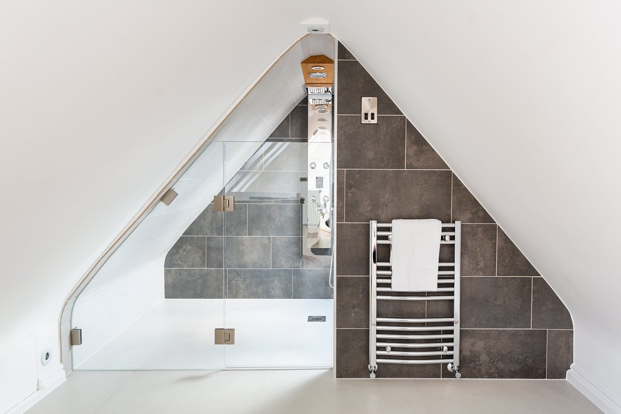Modern sloped ceiling bathroom with glass shower cubicle in new loft project