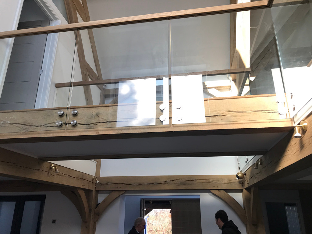 Modern mezzanine with glass railing and wooden beams.