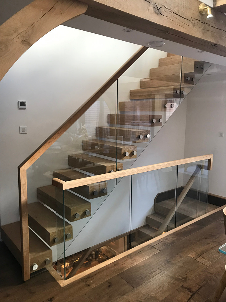 Modern wooden staircase with glass balustrade.